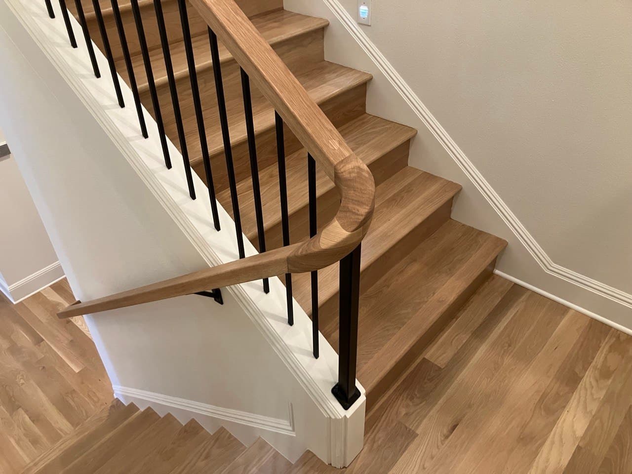 Custom white oak staircase with sculpted continuous handrail and black steel balusters — built by Stumptown Stairs, Portland, OR