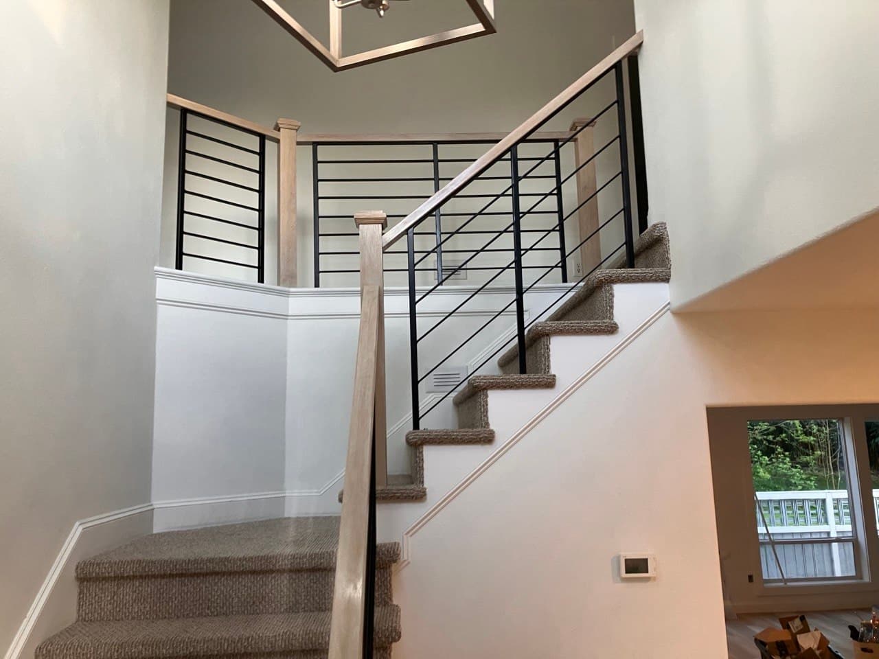 Finished stair installation — carpeted staircase with horizontal black steel railing and white oak posts by Stumptown Stairs, Portland, OR